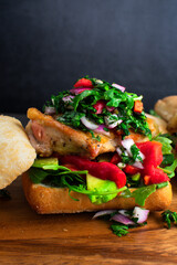 Chimichurri Chicken Sandwich on a Wooden Cutting Board: Open-faced sandwich topped with avocado, roasted peppers and arugula
