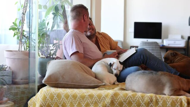 Happy gay couple spending time together with their pets at home while reading