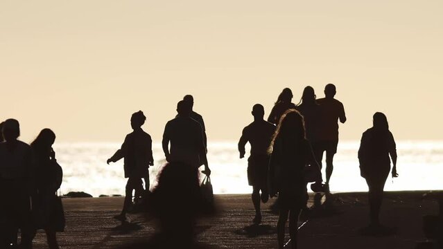 Athletic people running and a child riding a bicycle by the sea at sunset in the crowd of people