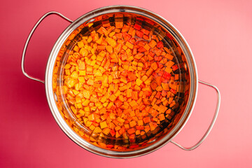 Diced Turmeric in a Small Pot with Liquid: Peeled and chopped fresh turmeric root floating in a small saucepan