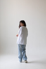 Beautiful brunette with curly hair in a white t-shirt and oversized jeans. Mock-up. Back view.