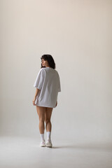 Attractive woman with curly hair in oversized t-shirt. Mock-up