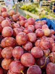 Bunches of grapes in a box in a supermarket. Pink grapes, close-up. Harvest of juicy pink grapes
