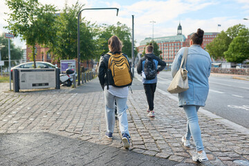 Back view of people walking along the street of a modern city