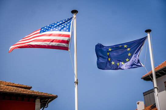 Flag of the United States next to the Flag of the European Union Waving Made on a Pole with Blue Sky in the Background