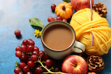 Cup of coffee with milk, waffles, apples and chocolate and yarn balls on a blue background with copy space. Cozy autumn concept. 