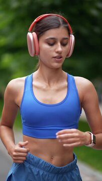 Running through the urban streets is a young girl in sports clothing and headphones.