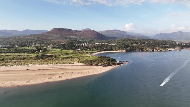 4k 60 FPS pullout shot of sandy beach bay with mountain scenery, a jetski riding the sea waves comes into view and follows camera