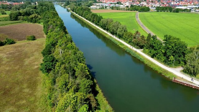 Aerial view of Main canal water body with bike path and trees near Volkach in Bavaria, Germany
