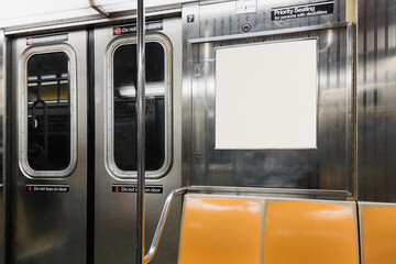 Interior view of a subway car in New York. There are yellow seats and a blank space for advertising signage.
