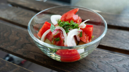 Vegetable salad in a transparent bowl. Tomato, onion, cucumber