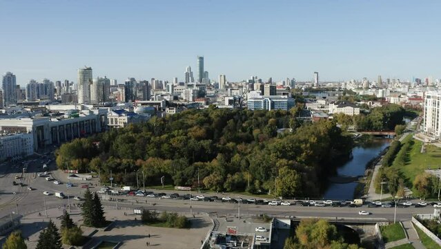 Aerial view of a modern big city with central streets on a summer day. Stock footage. Green park and river near buildings.