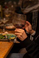 A glass of red wine in a woman's hand during a feast