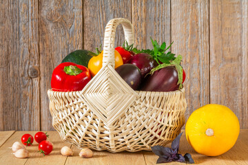 Fresh ripe organic vegetables in a wicker basket on a wooden table