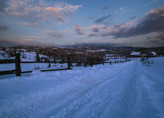 Night countryside road, hoases, hills, groves and farmlands in winter remote alpine mountain village. Ukraine, Voronenko.