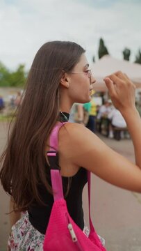 At the summer festival, a beautiful young woman enjoys a leisurely walk.