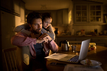 Worried young Caucasian couple going over their bills and home finances at night at home