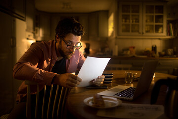Young businessman going through paperwork at night at home