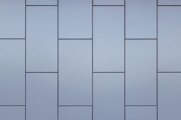 Outside wall of building covered with grayish blue painted metal rectangular panels - full-frame background and flat texture.