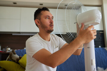 Mature man works to install a paddle fan on the ceiling at home - obrazy, fototapety, plakaty
