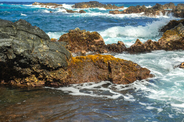 Sea background. Ocean wave crashing on rock coast with spray and foam before storm.