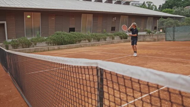 Teenager boy playing tennis on court