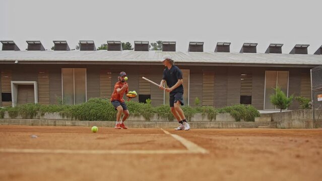 Coach teaches teenage son to play tennis