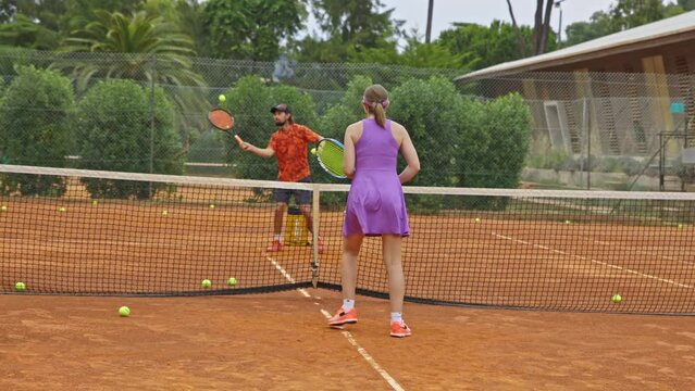 Adult man and woman play tennis on outdoors court