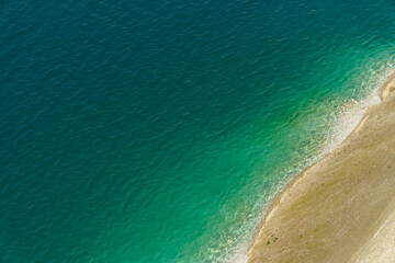 Obraz premium Aerial view of the steep coast with white sand on the shore of a clean and beautiful turquoise sea. Tropical sea beach in Indonesia. An empty deserted beach for a family holiday. Copy space