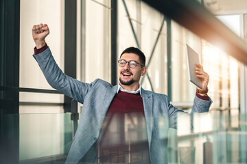 Young dedicated college student holding digital laptop expressing excitement and happiness about...