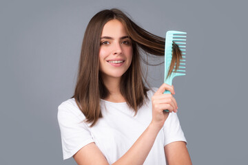 Close up portrait of happy beautiful girl with shiny hair with comb. Attractive smiling woman...