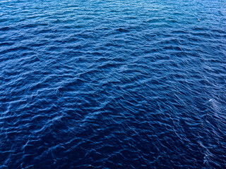 Blue water background. Wavy sea water surface. Close-up of blue water surface in the deep ocean. Blue background.