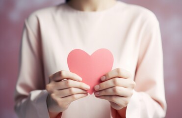 asian woman making heart shape with hands on pink background.