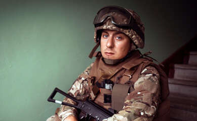A soldier sits on the stairs with a weapon., machine gun.