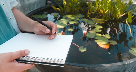Man is writing notes on a white paper, hands closeup.