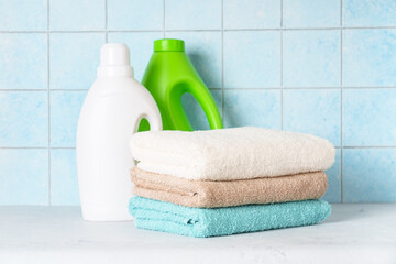Clean towels and detergent in the laundry or bathroom against blue wall.