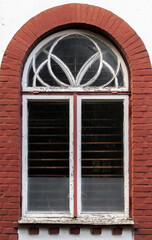 Fototapeta na wymiar Window with arch in white wooden frame in a stone wall