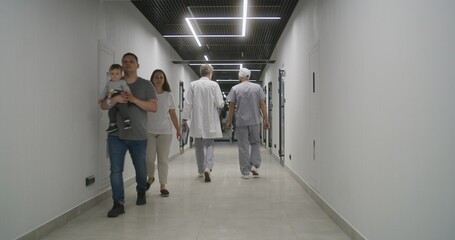 Doctor with male nurse walk the clinic corridor. Colleagues discuss treatment, diagnosis or medical...