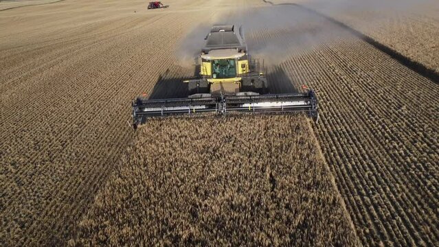 Rocky View County Alberta Canada, September 11 2023: Large New Holland Combine harvesting a hillside barley field with a dust trail in North America.
