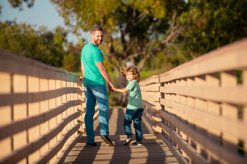 Fototapeta na wymiar Father with son walking on wooden bridge outdoor.