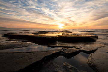Fototapeta na wymiar Waves on the rocks at the seaside at the sunset