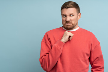 Confused man feeling disgust with serious face incredulously looking aside isolated on blue...