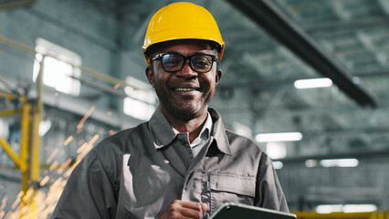African American architecor in protective casque hold tablet. Male engineer is posing and smiling...