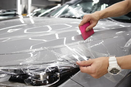 A car wrapping specialist applies a polyurethane film to the car. Selective focus. PPF protective film against chips and scratches. Car wrapping. 