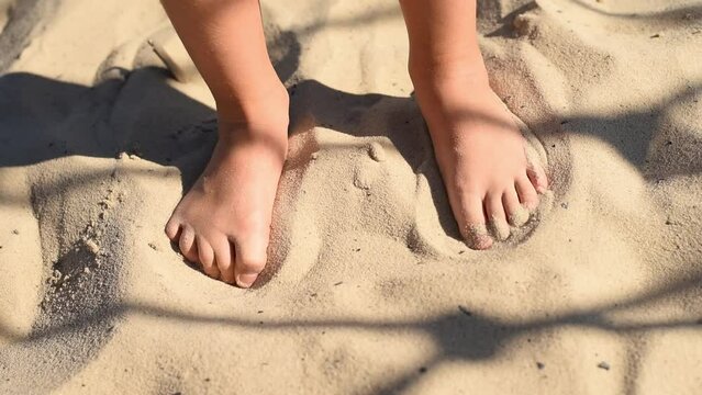 Bare healthy children's feet move  fingers in the sand