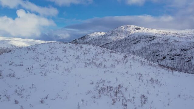 Background of snow covered mountain hills and blue sky on a sunny winter frosty day. 4k aerial drone traking view