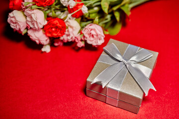 Silver Gift Box with a Bow and silk roses isolated on red