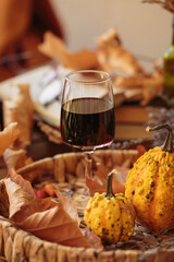 Glass of red wine on wooden table decorated with pumpkins and dried leaves outdoor. Autumn composition for Thanksgiving. Autumnal mood