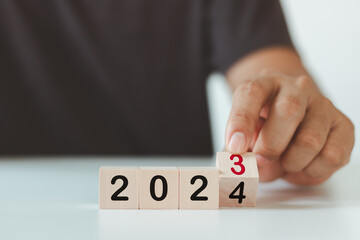2024 Happy New Year eve wooden blocks flip change hand white background. Countdown starting ending...