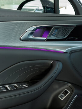 vertical photo of a door panel with ambient purple lighting and aluminum trim in a premium car